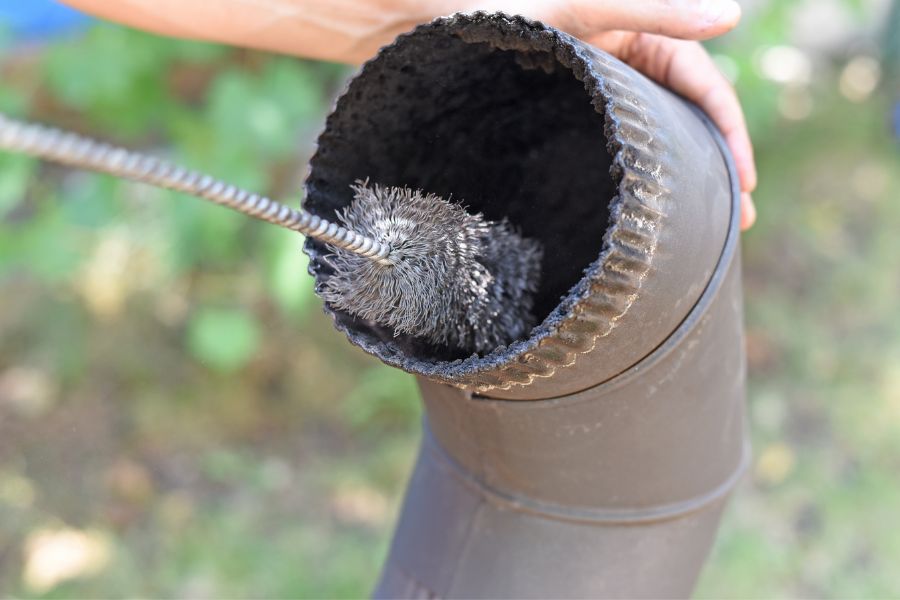 Cleaning wood stove chimney with a chimney brush