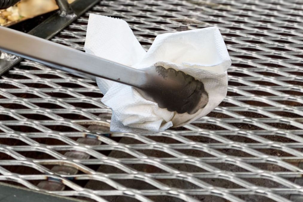 Applying oil to grill grate using paper towel