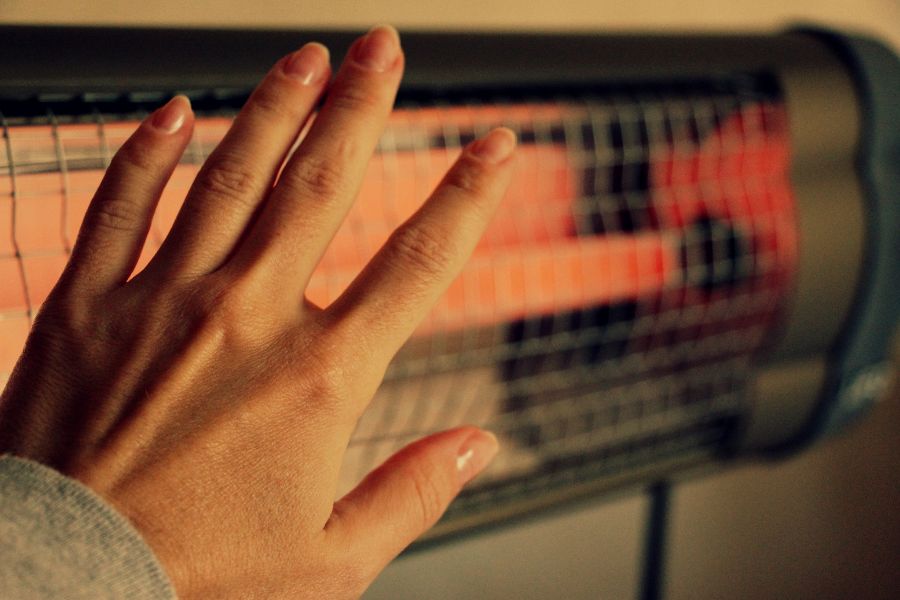 Woman warming hand at an infrared heater