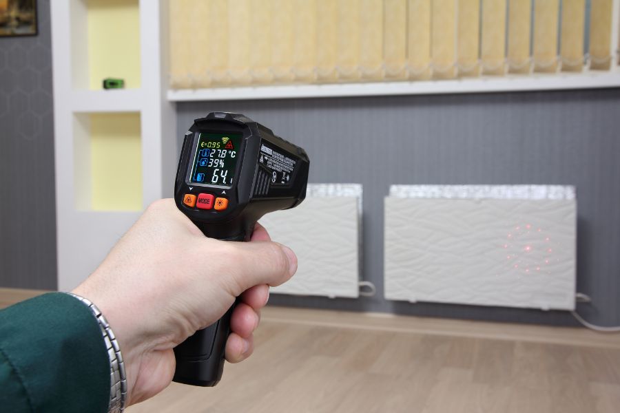Infrared Thermometer in hand measures heating radiator temperature