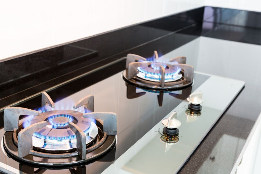 Glass-top gas stove with burning flames in the kitchen