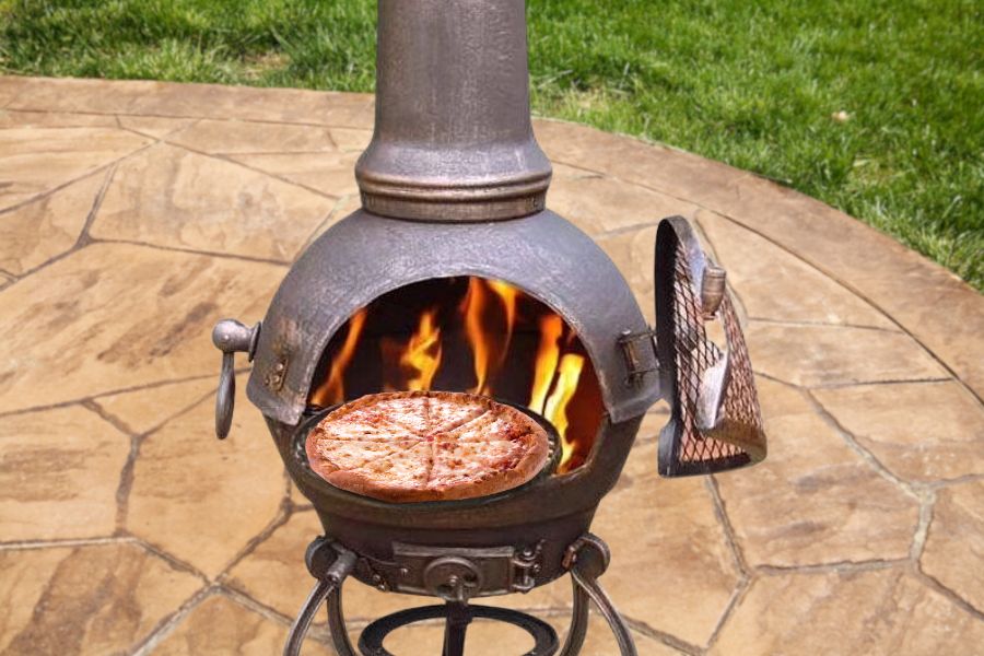 A burning chiminea and pizza on grilling rack