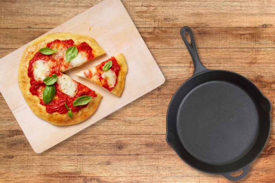 A pizza stone and cast ion pan on wooden table