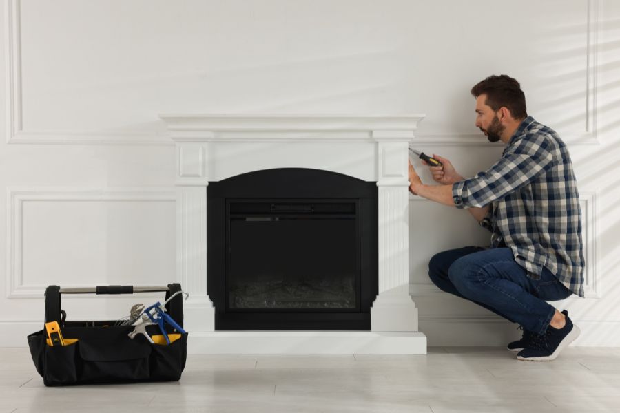 Man with screwdriver removing electric fireplace insert
