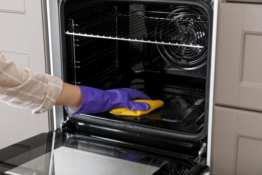 Woman cleaning electric oven in the kitchen 
