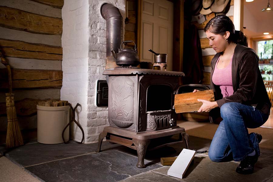 woman in pink long sleeve shirt standing beside black wood burner