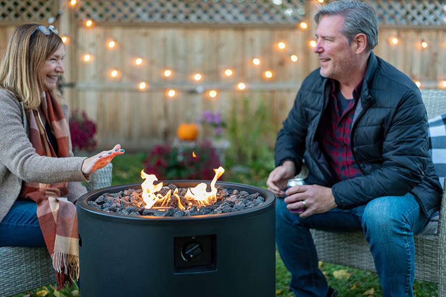 Middle age couple sitting by a backyard fire pit in autumn