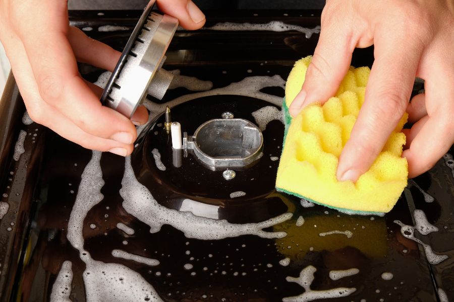 Cleaning gas stove with scrub sponge
